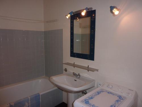une salle de bain avec un lavabo, un miroir et une baignoire dans l'établissement T2 avec balcon, parking privé, proche forêt, Mont-Dore - FR-1-608-212, à Le Mont-Dore
