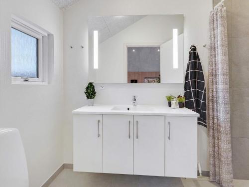 Un baño blanco con lavabo y espejo. en Luxury Retreat with Pool - By Traum Ferienwohnungen, en Bøtø By