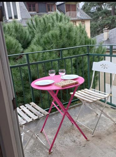 une table rose et deux chaises sur un balcon dans l'établissement Jean marc, à Luchon