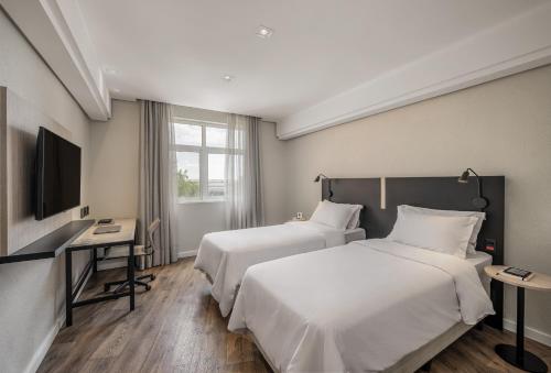 a hotel room with two beds and a television at Intercity Porto Alegre Aeroporto in Porto Alegre