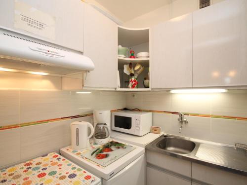 une petite cuisine avec un évier et un micro-ondes dans l'établissement Appartement 2 pièces avec balcon, parking et WiFi - 4 personnes - FR-1-608-117, à Le Mont-Dore