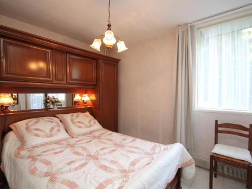 Schlafzimmer mit einem Bett, einem Fenster und einem Kronleuchter in der Unterkunft Appartement 2 pièces avec balcon, parking et WiFi - 4 personnes - FR-1-608-117 in Le Mont-Dore