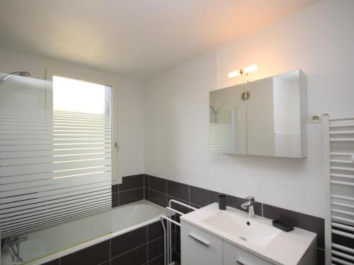 une salle de bain avec un lavabo, une baignoire et un miroir dans l'établissement Charmant T2 avec Wi-Fi, garage double, proche centre Mont-Dore et thermes - FR-1-608-114, à Le Mont-Dore