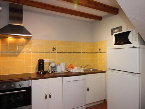 - une cuisine avec un réfrigérateur blanc et du carrelage jaune dans l'établissement T3 à La Bourboule, terrasse, wifi, proche centre et thermes - FR-1-608-128, à La Bourboule