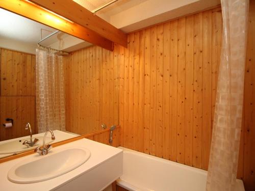 La salle de bains est pourvue de murs en bois, d'un lavabo et d'une baignoire. dans l'établissement Mont-Dore Studio 2* avec garage, 300m du centre - FR-1-608-148, à Le Mont-Dore
