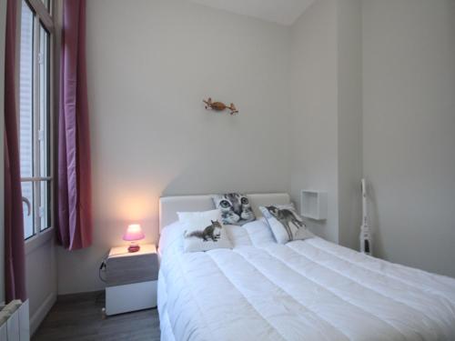 - une chambre dotée d'un grand lit blanc avec des chiens sur les oreillers dans l'établissement Charmant T2 avec WIFI en centre, proche thermes, tout équipé pour 4 pers., au Mont-Dore - FR-1-608-153, à Le Mont-Dore