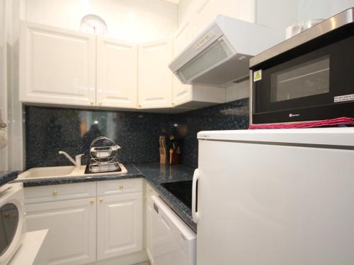 une cuisine avec des armoires blanches et un réfrigérateur blanc dans l'établissement Charmant T3 au Mont-Dore avec Balcon, à 100m du Centre et des Thermes - FR-1-608-155, à Le Mont-Dore