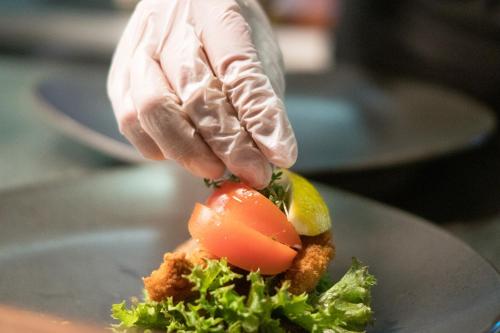 a person is cutting a tomato on a plate at Hotel Hans Egede in Nuuk