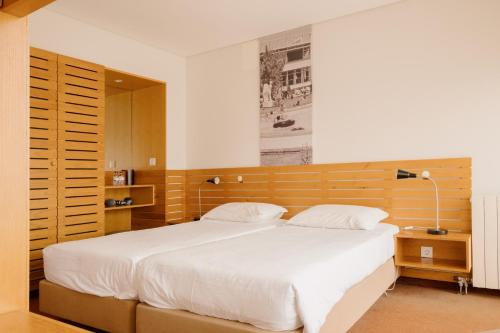 エシュポゼンデにあるParque do Rio Ofir Hotelのベッドルーム1室(大型ベッド1台、木製ヘッドボード付)
