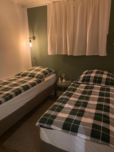 two beds in a bedroom with a checkered blanket at Ferienwohnung Schwarzwaldgrund in Baiersbronn