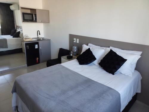 una camera d'albergo con un grande letto con cuscini neri di Flat América Pelinca Campos a Campos dos Goytacazes