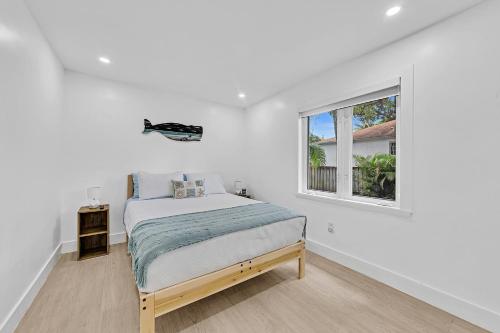 a white bedroom with a bed and a window at Welcome to Paradise! Secluded 4 bed, 3 bath, pool in Fort Lauderdale