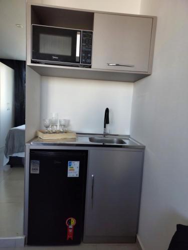 a kitchen with a microwave and a small refrigerator at Flat América Pelinca Campos in Campos dos Goytacazes