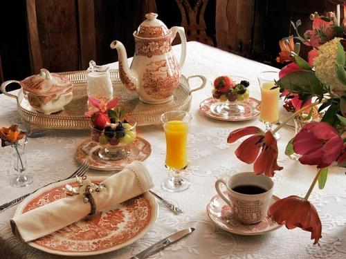 a table with plates and cups of coffee and a tea pot at Fisher House Victoria Bed and Breakfast in Victoria