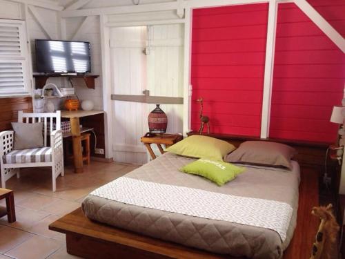 - une chambre avec un grand lit et un mur rouge dans l'établissement Charmant Bungalow Un p'tit coin de paradis, à Saint-François