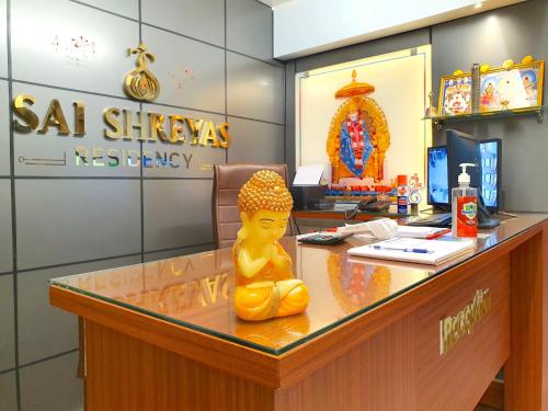 uma estátua amarela sentada numa secretária num escritório em Sai Shreyas Residency, Best Hotel near Bangalore Airport em Bangalore