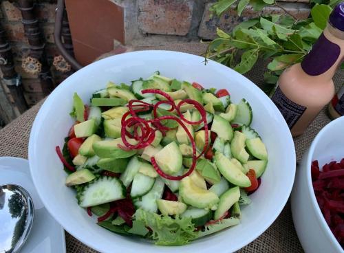 a bowl of salad with cucumbers and red onions on it at Modjadji Estate Lodge & Spa in Grietjie Nature Reserve