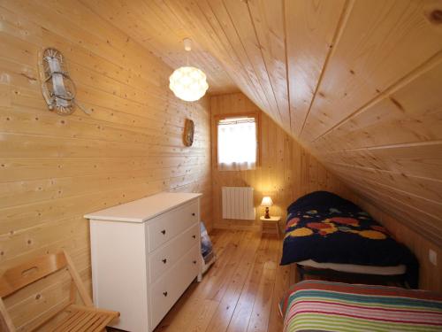 Cette chambre comprend un lit et une commode dans une cabane en rondins. dans l'établissement Chalet spacieux avec terrasse, Wi-Fi et parking - FR-1-608-15, à Le Mont-Dore