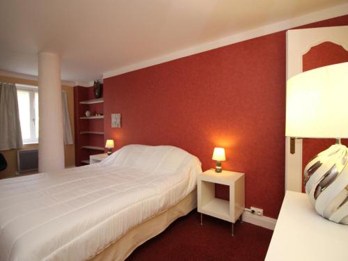 une chambre avec un lit blanc et un mur rouge dans l'établissement T2 La Bourboule Centre avec Wifi, 100m des Thermes, Jusqu'à 6 Pers. - FR-1-608-19, à La Bourboule