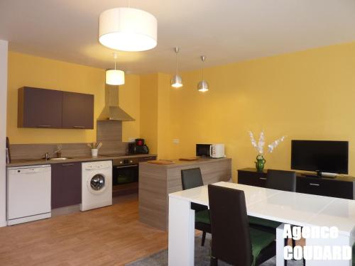 une cuisine avec des murs jaunes et une table avec des chaises dans l'établissement Charmant T3 rénové au centre du Mont-Dore avec Wi-Fi, proche thermes et marché. - FR-1-608-22, à Le Mont-Dore