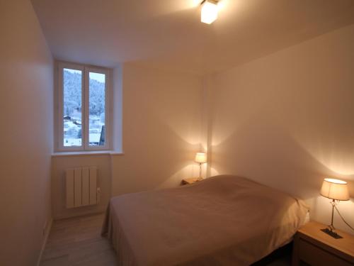 ein Schlafzimmer mit einem Bett und zwei Lampen und einem Fenster in der Unterkunft Mont-Dore: Beau Duplex T3 Rénové pour 6 Pers, 2 Chambres - FR-1-608-30 in Le Mont-Dore