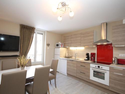 une cuisine avec une table à manger et un appareil rouge dans l'établissement Le Mont-Dore - Charmant T3 en plein centre-ville avec accès WiFi, proche thermes et commodités - FR-1-608-28, à Le Mont-Dore