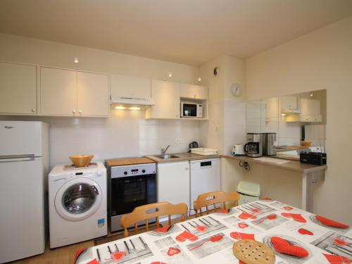 une cuisine avec une table et une machine à laver dans l'établissement La Bourboule T2 bis centre, parking, proche des thermes - FR-1-608-53, à La Bourboule