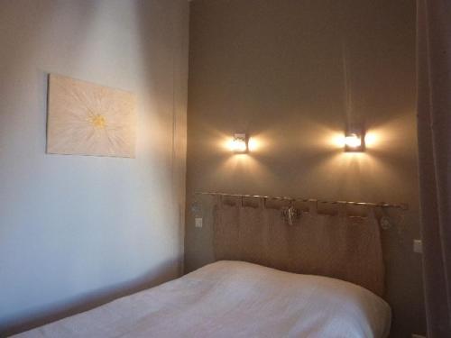 - une chambre avec un lit et deux lumières sur le mur dans l'établissement Charmant T1 au Mont-Dore, balcon, hyper centre, bien équipé, max 4 pers. - FR-1-608-38, à Le Mont-Dore