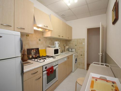 une cuisine avec une cuisinière et un micro-ondes dans l'établissement Lumineux T4 à La Bourboule, 6 pers, proche centre, tout équipé, cour privée, 68m² - FR-1-608-39, à La Bourboule