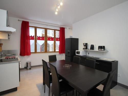 - une cuisine avec une table à manger et des rideaux rouges dans l'établissement Bel Appartement T3 avec WIFI au Centre du Mont-Dore, Proche des Thermes - FR-1-608-49, à Le Mont-Dore