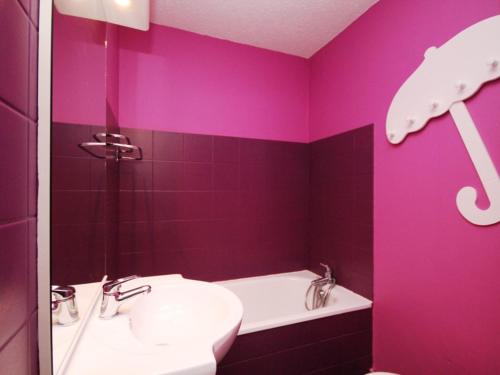 La salle de bains est pourvue de murs violets, d'un lavabo et d'une baignoire. dans l'établissement Mont-Dore Duplex 40m² avec Balcon, Wifi et Parking - FR-1-608-51, à Le Mont-Dore