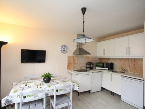 une cuisine avec des armoires blanches et une table avec des chaises dans l'établissement Le Mont Dore – Beau T2 avec balcon, wifi et parking, idéal pour 4 personnes - FR-1-608-86, à Le Mont-Dore