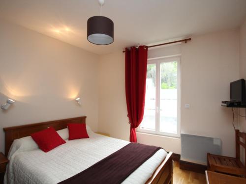 une chambre avec un lit avec des oreillers rouges et une fenêtre dans l'établissement Le Mont Dore – Beau T2 avec balcon, wifi et parking, idéal pour 4 personnes - FR-1-608-86, à Le Mont-Dore