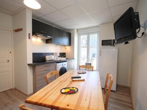 une cuisine avec une table en bois et des chaises ainsi qu'une salle à manger dans l'établissement Appartement T3 au Mont-Dore avec WIFI et balcon, près du centre - FR-1-608-84, à Le Mont-Dore