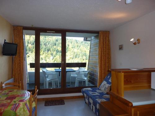 - une chambre dotée d'une grande fenêtre avec une table et des chaises dans l'établissement Studio cosy avec balcon, wifi et parking au Mont-Dore - FR-1-608-93, à Le Mont-Dore