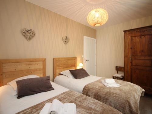 a bedroom with two beds and a chandelier at Beau T3 avec terrasse, parking et wifi à 300m des Thermes du Mont-Dore - FR-1-608-79 in Le Mont-Dore