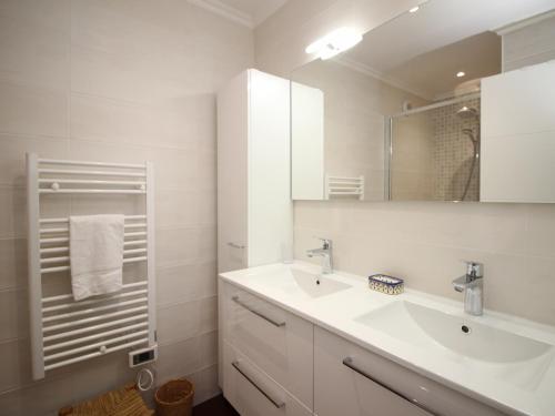 a white bathroom with a sink and a mirror at Mont-Dore : T2 spacieux avec terrasse, 300m des thermes, résidence rénovée, parking privé - FR-1-608-98 in Le Mont-Dore