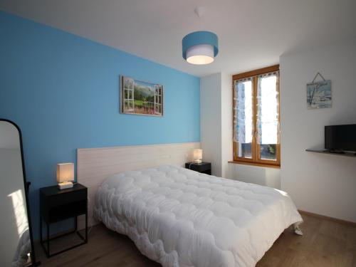 Un dormitorio con una cama blanca y una pared azul. en Bel Appartement T3 avec WIFI et Parking, Résidence de Standing, 300m des Thermes au Mont-Dore - FR-1-608-87, en Le Mont-Dore
