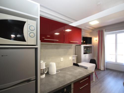 une cuisine avec des armoires rouges et un micro-ondes dans l'établissement Mont-Dore : Studio Centre avec Ascenseur - 2 Pers - Cuisine Équipée - FR-1-608-103, à Le Mont-Dore