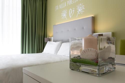 a bedroom with a bed and a table with a container with seashells at Hotel Amburgo in Bibione