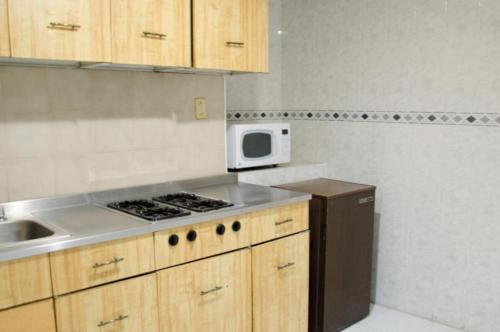 a kitchen with a stove and a microwave at Hotel Real del Sur in Mexico City