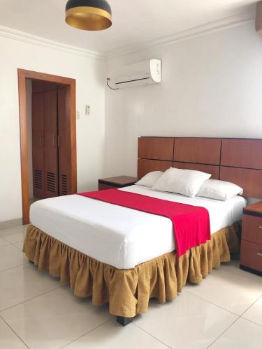 a bedroom with a large bed with a red blanket at Hoteles en Guayaquil - Suites Guayaquil Cerca del Aeropuerto in Guayaquil