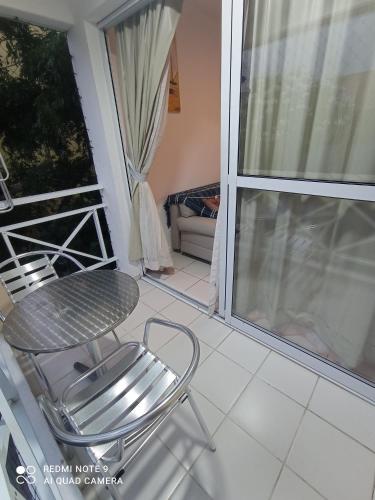 a chair on a balcony with a table and a window at Village Hospedagens in Natal