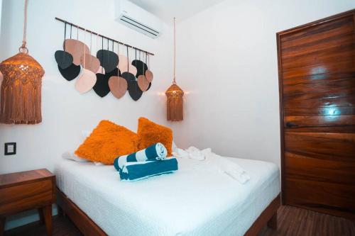 a bed with orange pillows and a blue bag on it at La HouseFina ground floor 1 in Holbox Island