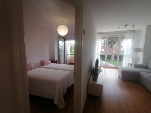 a bedroom with a bed and a living room with a couch at Apartamento céntrico con piscina y garaje in Suances