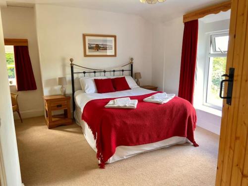 a bedroom with a large bed with a red blanket at Scenic Welsh Cottage in the Brecon Beacons in Crickhowell