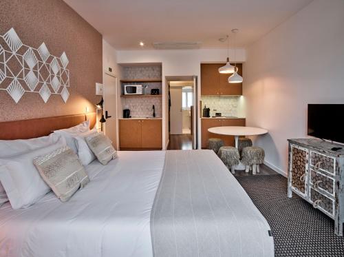 a bedroom with a large white bed and a kitchen at The Bastion Elvas Apartments in Elvas