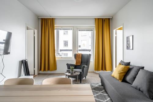 a living room with yellow curtains and a couch at Hiisi Homes Turku Ratapiha in Turku