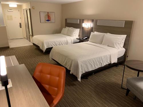 a hotel room with two beds and a chair at Holiday Inn Express Hotel & Suites Hermosa Beach by IHG in Hermosa Beach