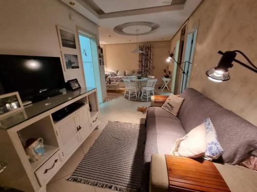 sala de estar con sofá y TV de pantalla plana en Flat com lareira em Campos do Jordão, en Campos do Jordão